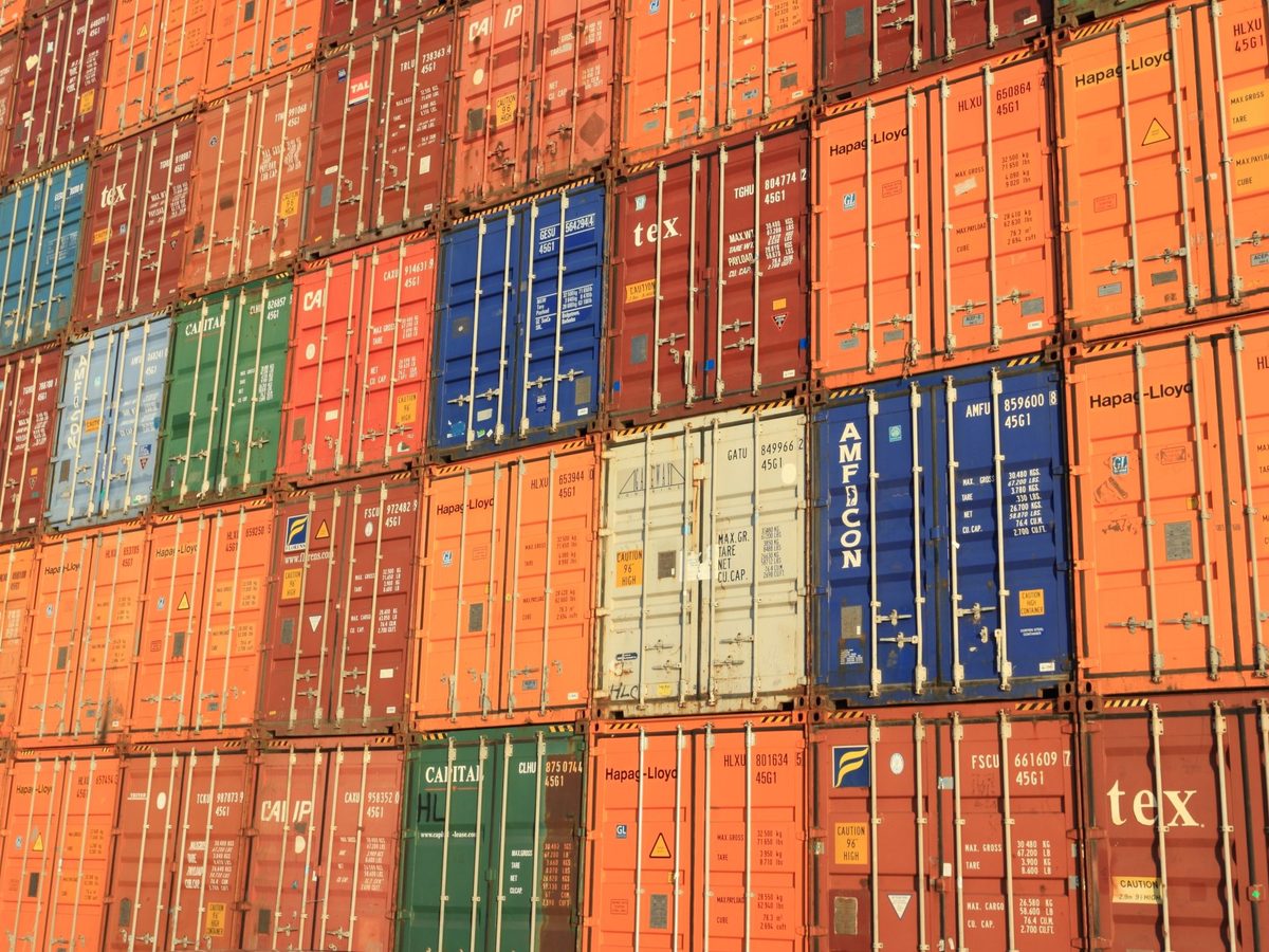 A wall of stacked shipping containers in a storage yard