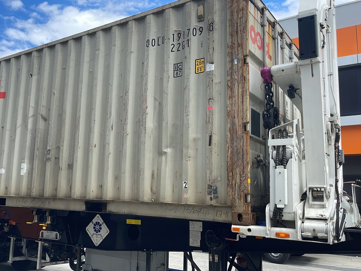 A 20-foot container loaded on an Aardiv side loader trailer outside a warehouse